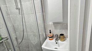 A bathroom with a shower, a sink, and a cabinet. - Lovely Studio in Town Centre (Reading)