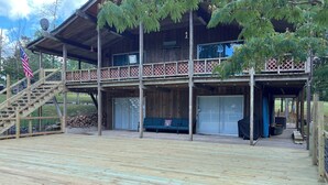 Uma cabana de madeira com varanda coberta, escadaria e uma bandeira.