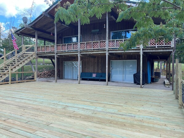 A wooden cabin with a covered porch, a staircase, and a flag.
