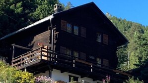 A wooden chalet with a balcony, surrounded by greenery and a hill. - Outside: 4-room chalet for 6 (or even 7) people, with balconies, unobstructed view, very well locate (St-Luc)