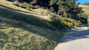 A wooden house with a balcony, surrounded by trees and grass on a hillside. - Outside: 4-room chalet for 6 (or even 7) people, with balconies, unobstructed view, very well locate (St-Luc)