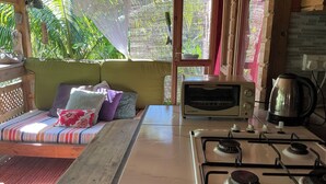 Une pièce confortable équipée d’un canapé-lit, d’une cuisinière à gaz, d’un grille-pain et d’une bouilloire.