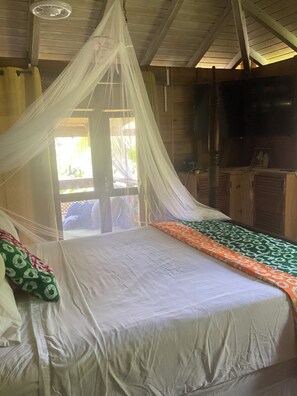 A room with a bed, a window, and a television. - Bauhinia Tropical 2 bedroom Retreat Cottage (Trafalgar Road)