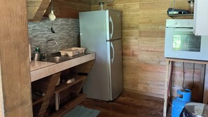 Une cuisine de taille réduite, équipée d’un réfrigérateur, d’un évier et d’étagères en bois.