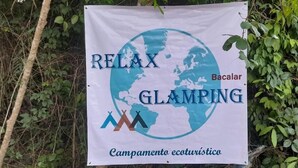 Une bannière faisant la publicité d’une expérience de «glamping» relaxante à Bacalar, avec des illustrations représentant un globe terrestre et des montagnes.