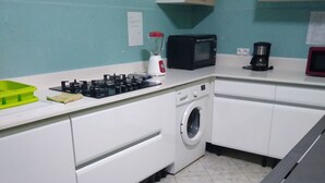 Cocina compacta equipada con estufa a gas, microondas, cafetera y lavadora.