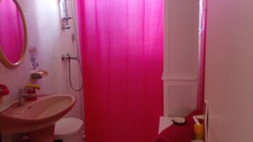 Een badkamer met een roze douchegordijn, een wastafel, een spiegel en een toilet.