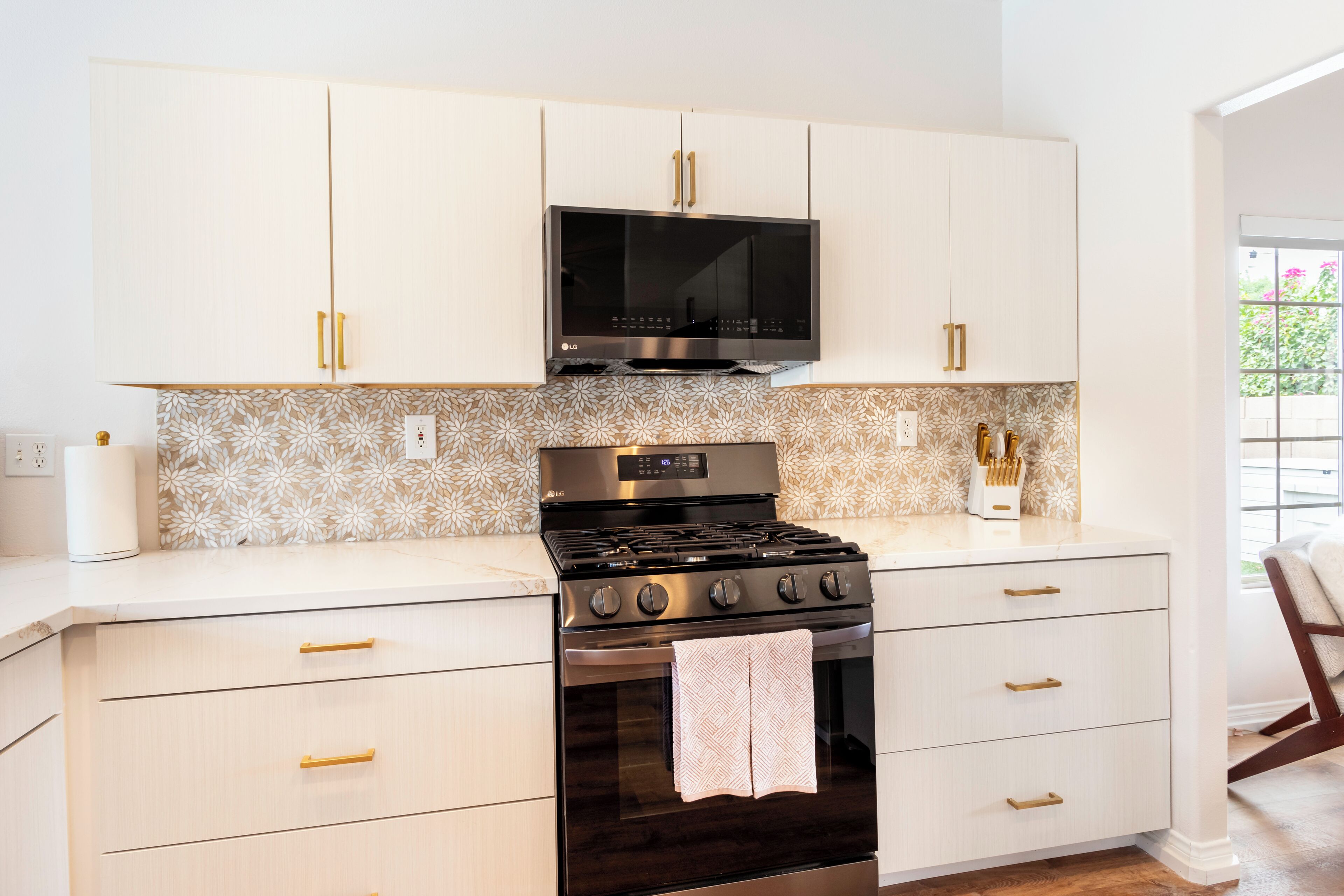 Et køkken med hvide skabe, en stålkomfur og en mikrobølgeovn over.