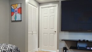 Een moderne slaapkamer met een bed, een televisie en een deur naar een andere kamer.