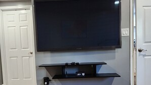 Een moderne woonkamer met een flatscreen-televisie aan de muur, een inbouwkast eronder en een houten vloer.