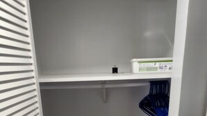 Een kleine, afgesloten kast met een witte binnenkant, een houten vloer en een witte deur met een handgreep.