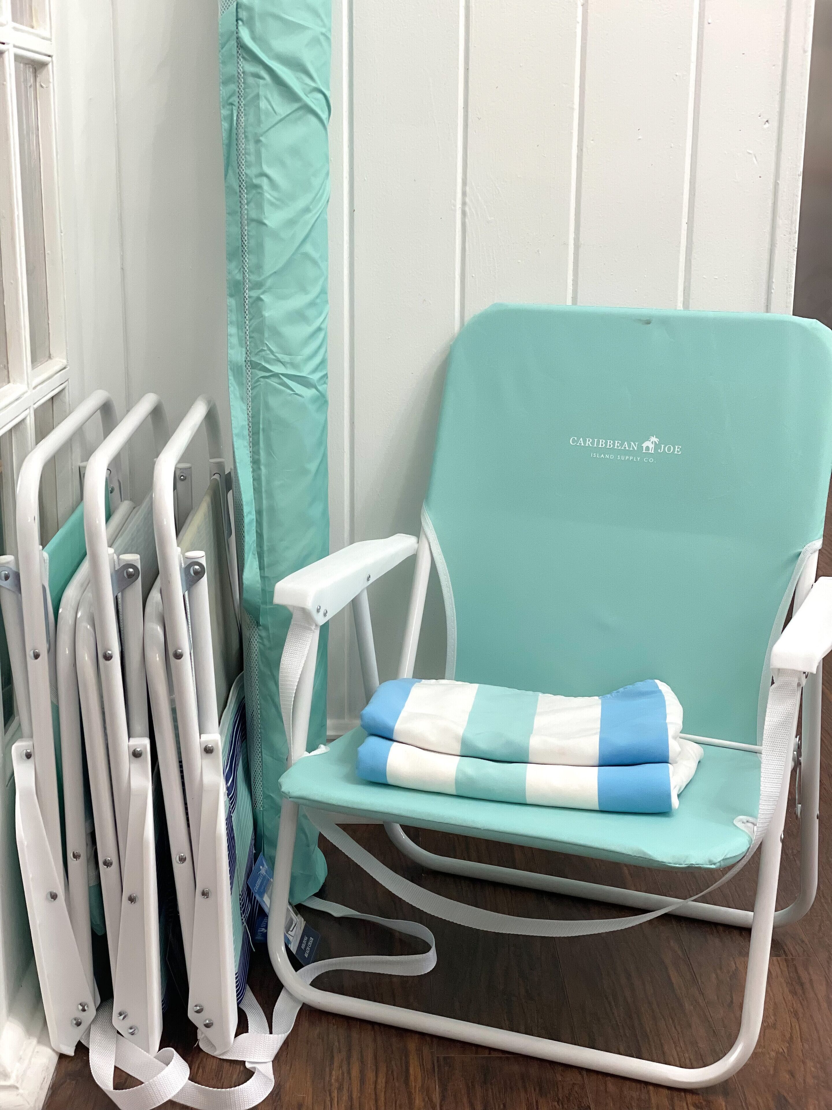 A teal hospital bed with a blue and white striped pillow, white railings, and a white wall with a window.
