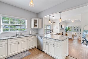 Une cuisine moderne avec des meubles blancs, des plans de travail en granit et un lave-vaisselle encastré.