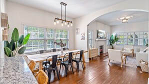 Un salón amplio con una mesa de comedor de madera, sillas negras y una chimenea.