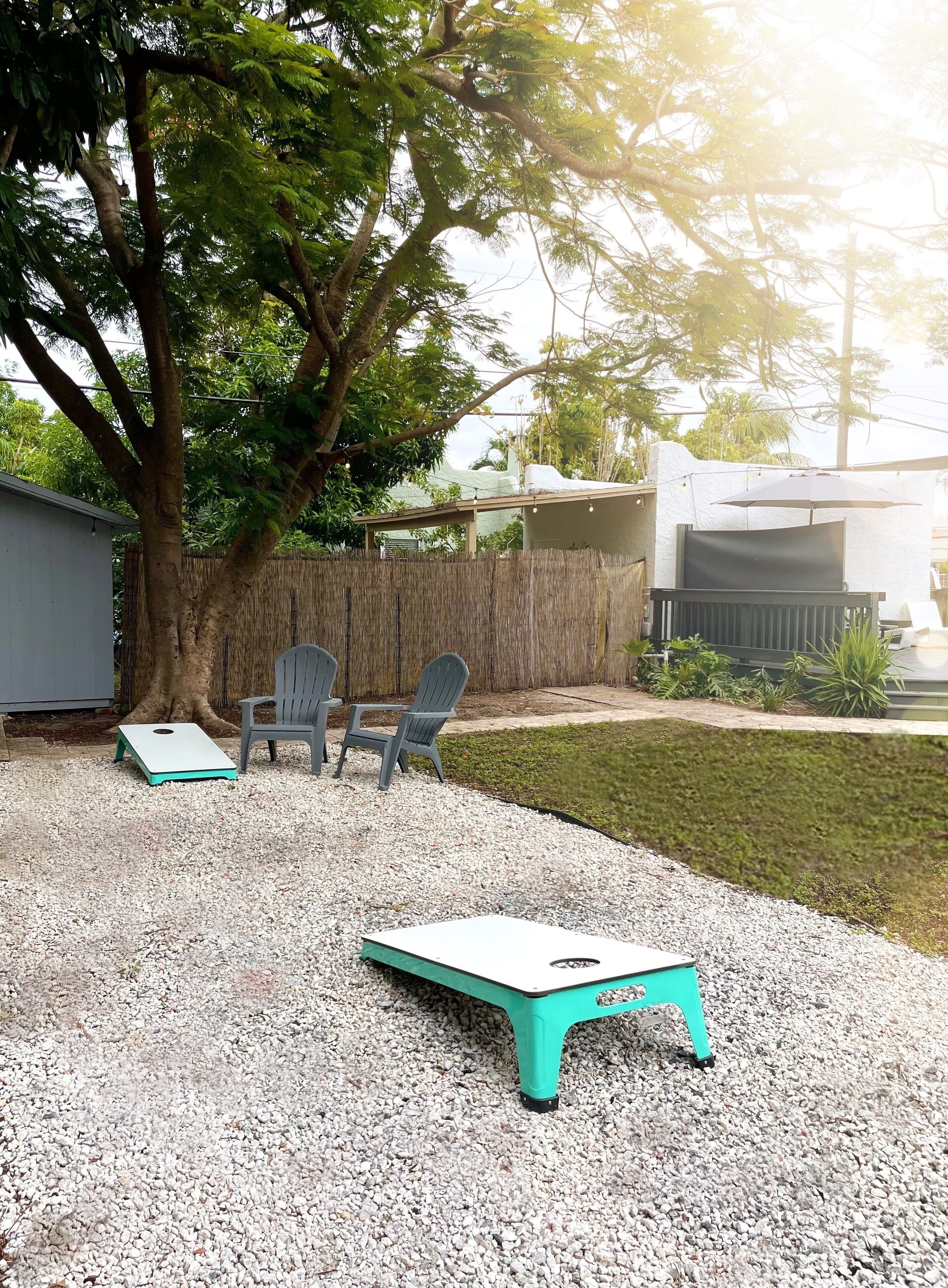 A backyard with a table and chairs, a tree, and a fence.
