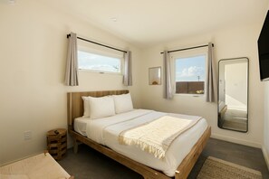 Un dormitorio con una cama de madera, una mesita de noche, un espejo y una ventana con cortinas.