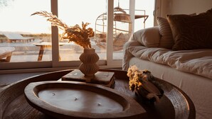 A cozy living room with a large window, a wooden tray with a candle, and a vase with dried flowers. - Casa Bella - Private Getaway w/ Pool - Spa - Views (Landers)