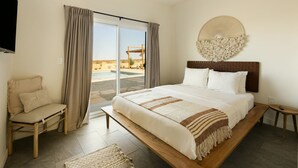 A bedroom with a large bed, a bench, a TV, and a view of a pool and desert landscape. - Casa Bella - Private Getaway w/ Pool - Spa - Views (Landers)