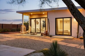 Una casa moderna con un patio amoblado, que incluye una zona de estar y un ventanal grande.