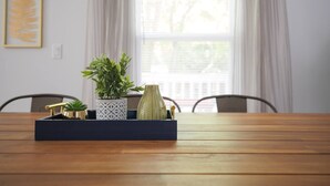 Une table en bois sur laquelle se trouve un plateau contenant une plante en pot, un vase décoratif et un objet de couleur dorée.