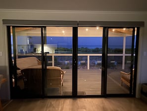 Une pièce dotée d’une porte-fenêtre coulissante donnant sur une terrasse extérieure avec vue sur l’océan.