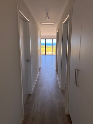 A hallway with a view of the ocean through large glass doors at the end. - A new coastal home to relax & escape to, on the beautiful Yorke Peninsula in SA. (Marion Bay)
