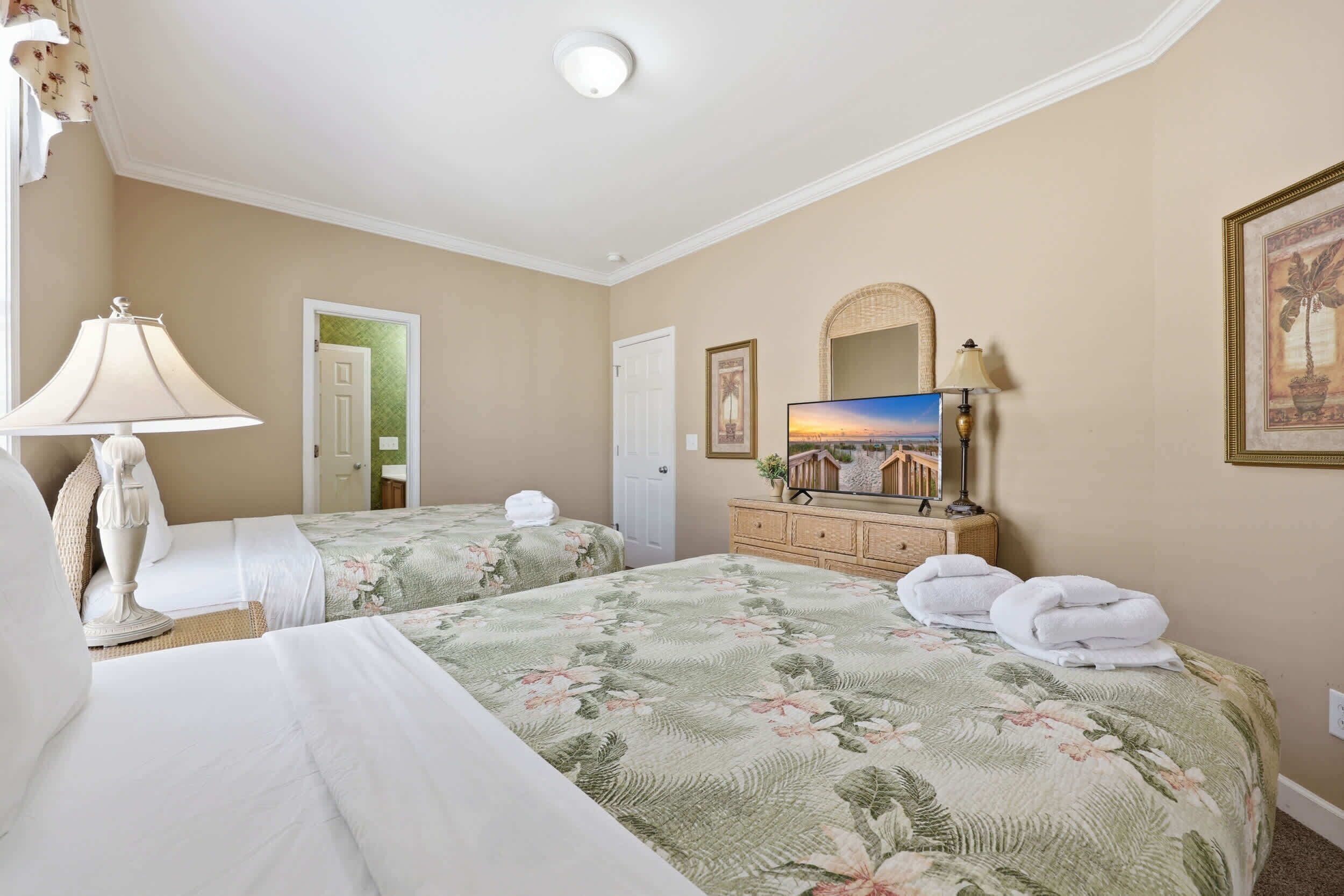 Une chambre d’hôtel avec deux lits, une télévision, une commode et un miroir.