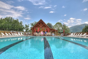 Une piscine avec des chaises longues et un pavillon en bois en arrière-plan.