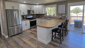 A modern kitchen with white cabinets, stainless steel appliances, and a wooden island with bar stools. - Unique renovated 4 bedroom home on private corner lot (Forks)