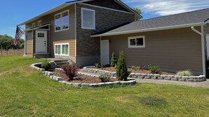 A two-story house with a stone facade, a front porch, and a landscaped garden. - Unique renovated 4 bedroom home on private corner lot (Forks)