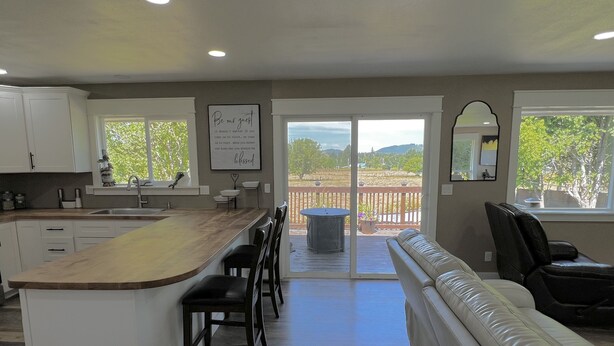 A spacious kitchen with a large island, a dining area with a bench, and a sliding glass door leading to a deck. - Unique renovated 4 bedroom home on private corner lot (Forks)