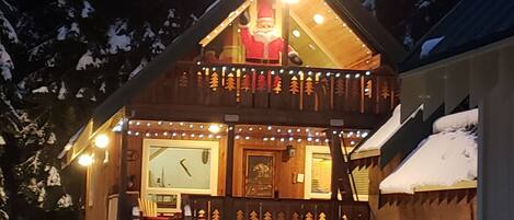 Une cabane en bois dotée d’un balcon, d’un escalier menant à l’entrée et de la neige au sol.