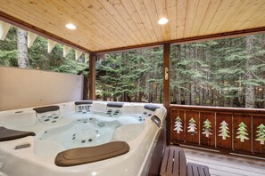 Un jacuzzi con controles, rodeado por una terraza de madera y vistas al bosque.