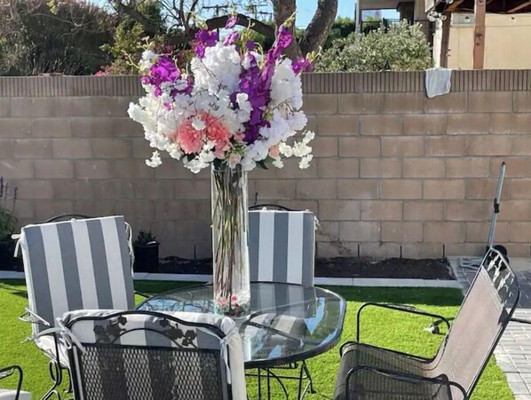 Relax in style with a round table and two lounge chairs on a patio surrounded by a beautifully manicured lawn.
