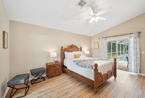 Un dormitorio con una cama de madera, un banco, una mesita de noche y un ventilador de techo.