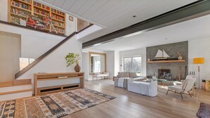 Ein großzügiger Wohnbereich mit Treppe, Kamin und Bücherregal.