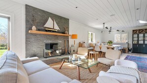 Ein modernes Wohnzimmer mit Kamin aus Stein, einem Glastisch und bequemen Sitzmöglichkeiten.