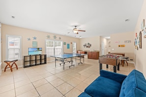 A spacious living area with a foosball table, a ping pong table, and a television. - 5BR | Sleeps 17 | Pool | Close To The Beach | 7092 (North Myrtle Beach)