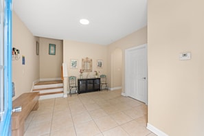 A hallway with a staircase, a console table with chairs, and a white door. - 5BR | Sleeps 17 | Pool | Close To The Beach | 7092 (North Myrtle Beach)
