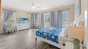 A bedroom with a bed, a desk, a chair, a TV, and a balcony. - 5BR | Sleeps 17 | Pool | Close To The Beach | 7092 (North Myrtle Beach)