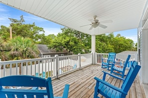 A covered outdoor deck with blue chairs, a white railing, and a ceiling fan. - 5BR | Sleeps 17 | Pool | Close To The Beach | 7092 (North Myrtle Beach)