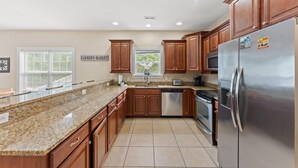 A kitchen with granite countertops, wooden cabinets, stainless steel appliances, and a window with blinds. - 5BR | Sleeps 17 | Pool | Close To The Beach | 7092 (North Myrtle Beach)