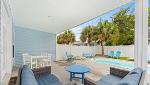 An outdoor patio with wicker furniture, a pool, and palm trees. - 5BR | Sleeps 17 | Pool | Close To The Beach | 7092 (North Myrtle Beach)