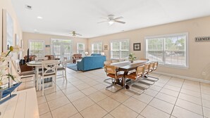 A spacious living area with a dining table, chairs, a blue sofa, and a ceiling fan. - 5BR | Sleeps 17 | Pool | Close To The Beach | 7092 (North Myrtle Beach)