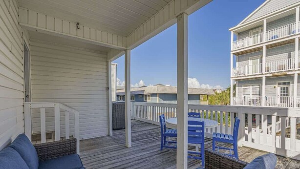 A covered outdoor area with wicker furniture and a white railing. - 6BR | Sleeps 16 | Pool | Steps To The Beach |20427 (North Myrtle Beach)