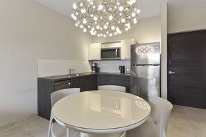 Una cocina moderna con una isla central, una mesa de comedor con sillas y una lámpara de araña grande.