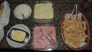 Ett buffébord med olika sorters mat, inklusive ost, skinka och pommes frites.