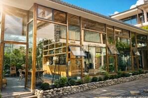 Un edificio moderno con ampie vetrate, un vialetto in pietra e cielo sereno.