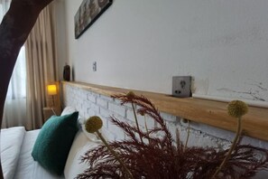 A hotel room with a white bed, teal pillow, and a wooden headboard. - Dali Village Inn (Dali City)