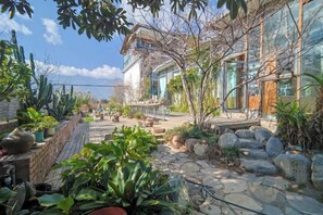 A courtyard with a stone pathway, potted plants, and a building with large windows. - Dali Village Inn (Dali City)